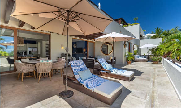 Outdoor patio lounge area with blue-and-white striped chaise loungers, umbrellas, and open-air dining under a covered terrace, Punta Mita villa