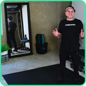 Video thumbnail for a 30 minute cardio class, man standing on a mat in a home gym with a mirror and exercise equipment behind him.
