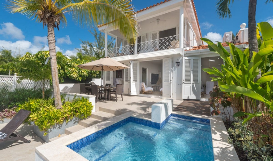 White two-story Caribbean villa with tiled roof and private plunge pool surrounded by palm trees and tropical gardens, Barbados vacation rental